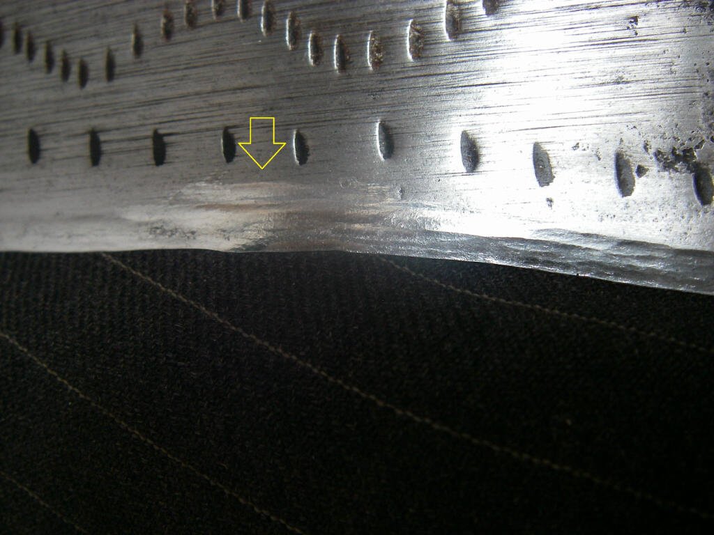 A nicely peened blade edge. Arrow points to repaired damage. 